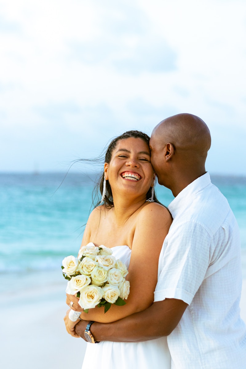 a newlywed couple hugging on the beach after the ceremony and making insurance updates